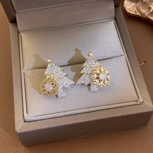 Golden rotating Christmas tree stud earrings with white zircons in a dark jewelry box