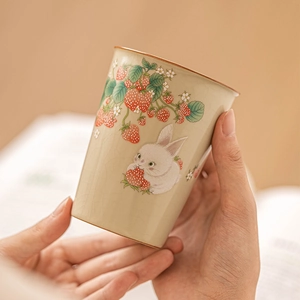 Ru-kiln ceramic teacup featuring strawberry rabbit patterns held in hand with natural light