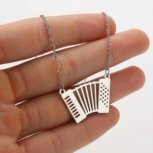 Macro détaillée d'un collier pendentif accordéon argenté tenu à la main avec détails précis