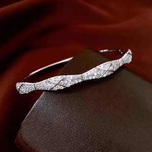 Vue macro d'un bracelet croisé argenté serti de zircons sur fond de satin rouge