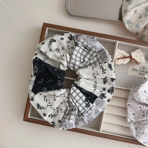 Detail of a large black and white patchwork scrunchie with floral and checkered patterns
