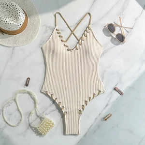 Detail of cream ribbed one-piece swimsuit with lace-up eyelets and cross straps