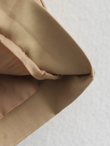 Close-up of khaki trench coat fabric showing durable twill texture and neat stitching