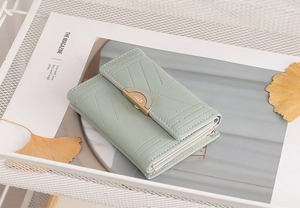 Detail of mint green tri-fold wallet featuring V-shaped stitching and gold clasp closure