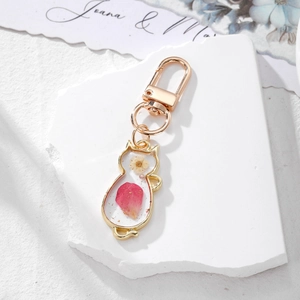 Pink real dried flower cat-shaped keychain with gold alloy frame on white stone