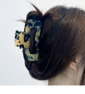 Detail of a large leopard print acetate claw clip securing hair in a modern French twist