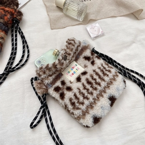 Détail d'un sac à téléphone en peluche à motif floral avec bandoulière tressée