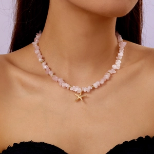 Necklace detail of pink crystal gravel beads with a golden starfish pendant on neck