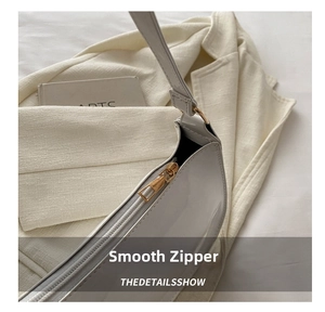 Detail of smooth gold zipper on white patent leather underarm bag with artsy background