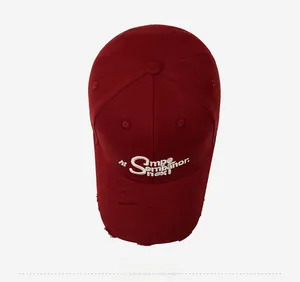 Detailed close-up of distressed brim and 3D embroidery on burgundy vintage baseball cap