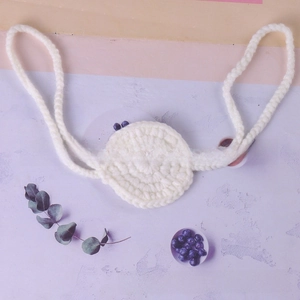 Detail of white handmade crochet circular pad with hanging ties for novelty nose mask accessories