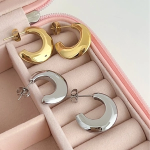 Close-up of gold and silver C-shaped stainless steel earrings in a pink jewelry box