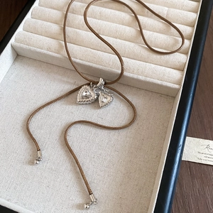 Detail of silver heart pendants with cubic zirconia on a brown braided wax cord
