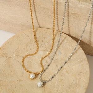Elegant gold and silver stainless steel pearl pendant necklaces on marble base