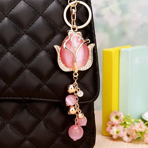 Pink gemstone rose keychain with rhinestones shown on black quilted leather handbag