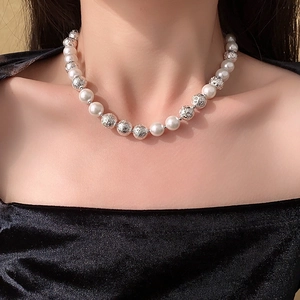 Detail view of a minimalist necklace with white pearls and textured silver beads on model