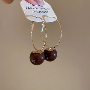 Macro view of gold hoop earrings with deep red resin cherry pendants and S925 silver needles