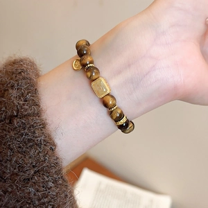 Tiger eye beaded bracelet with hollow gourd pendant worn on a warm knit sweater sleeve