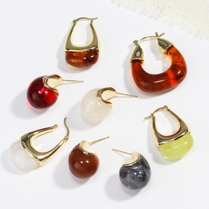 Flat lay of vintage U-shaped resin and gold metal earrings in various colors and patterns