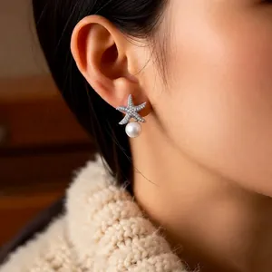 Starfish pearl earrings with cubic zirconia stones worn by model in a cozy setting