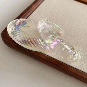Detail view of iridescent geometric resin bracelet with twisted texture on linen tray