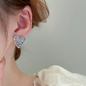 Macro detail of heart-shaped earrings with icy crystal texture and silver metal edges