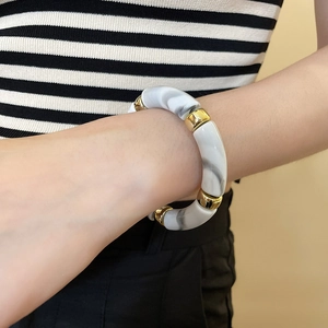 Detail of acrylic iridescent marble bracelet with gold beads worn on a wrist