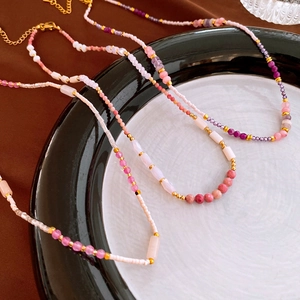 Detail view of handcrafted beaded necklaces with pink stones and gold lobster clasp