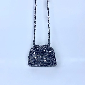 Detailed view of black metallic discs woven on a handmade sequin crossbody mini bag