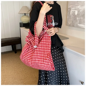 Detail of red checkered canvas tote bag with 'good' decorative buckle for daily use