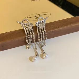 Detailed view of silver-tone tassel earrings with rhinestones and pearl pendants