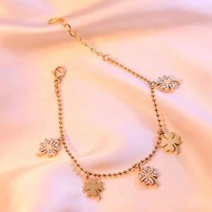 Gold plated four leaf clover bracelet with sparkling zircons on pink silk background