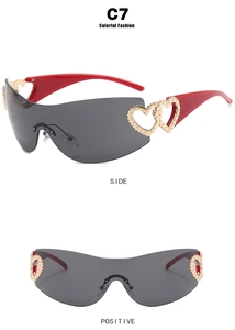 Detail of red Y2K wraparound sunglasses featuring golden heart accents and grey lenses