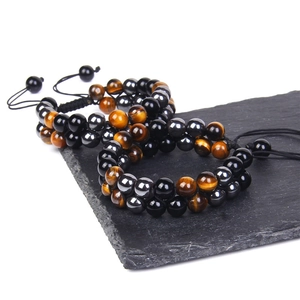 Close-up of tiger eye and obsidian beaded bracelets on stone with adjustable cord