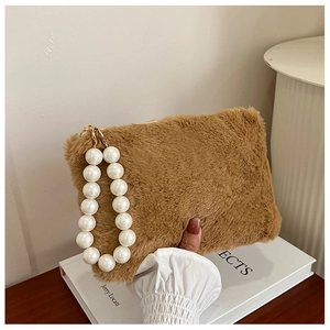 Close-up of brown plush handbag featuring a decorative white pearl handle and soft texture