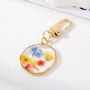 Detailed macro of golden keychain featuring real dried flowers in transparent resin