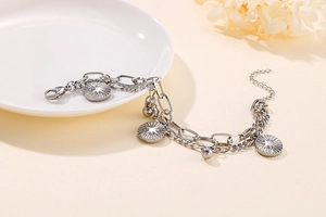 Detail view of double-layered silver chain bracelet with sunburst star coin pendants