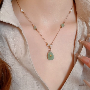 Vue macro d'un pendentif en pierre verte avec étoile dorée sur une chemise en lin