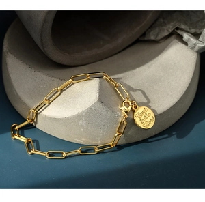 Close-up of golden paperclip chain bracelet with engraved Trust in the Lord pendant