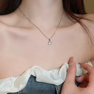 Close-up of minimalist silver necklace featuring a glowing white cat-eye stone pendant