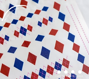Macro detail of red and blue Argyle pattern nail sticker with fine texture and pink dots