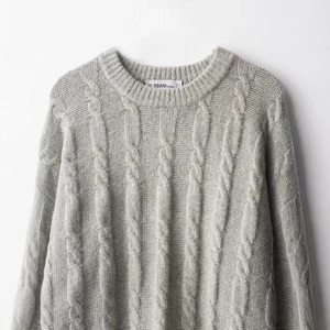 Classic grey cable knit round neck sweater with thick texture on white background