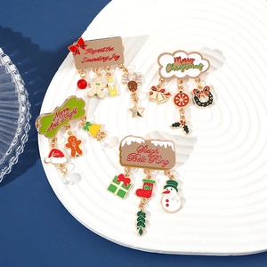 Macro shot of four festive Christmas enamel brooches with holiday charms on a tray