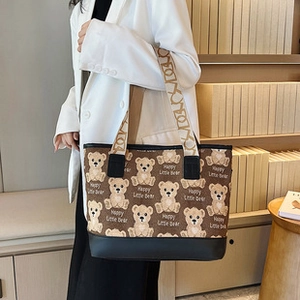 Detail of canvas tote bag with teddy bear pattern and wide textured strap worn by model
