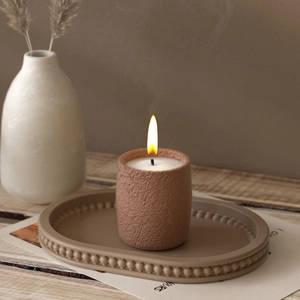 Detailed view of handmade beaded edge oval tray with candle in warm brown terracotta