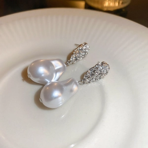 Baroque pearl drop earrings with silver textured metal on a decorative white plate