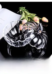 Close-up of a pumpkin-shaped glass storage jar with a lid on a black mirror surface