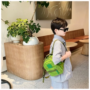 Gros plan d'un sac à bandoulière en nylon vert pour enfants avec un écusson carré