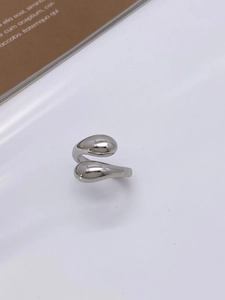 Detailed view of a silver teardrop ring on a white surface with vintage paper accents