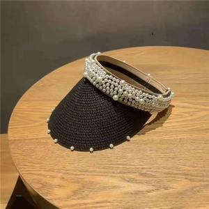 Close-up of black straw sun visor featuring elegant large pearl embellishments